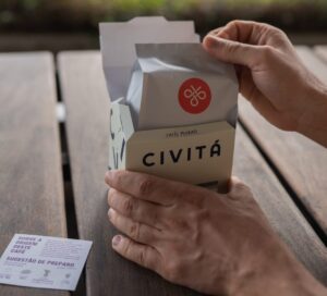 Mãos abrindo uma embalagem de café Civitá