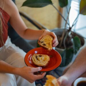 Cliente segurando um croissant sobre prato vermelho